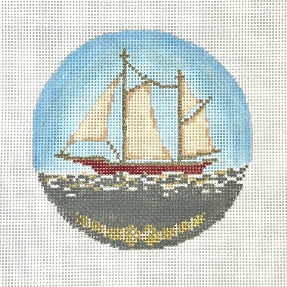 Needlepoint canvas featuring a three-masted sailboat with cream sails and a red hull on gray water, set within a light blue circular background and accented with a gold decorative border at the bottom.