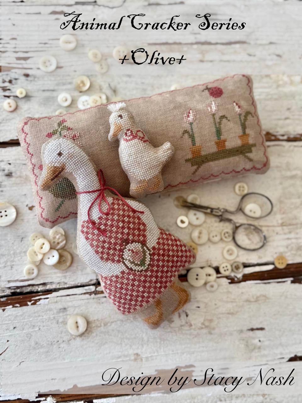 Cross stitch pillow of a goose, a smaller gosling stitched pillow and rectangular floral stitched pinkeep.