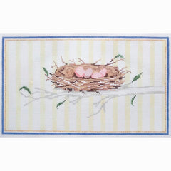 Needlepoint canvas featuring a bird’s nest with three pale pink eggs resting on a branch, surrounded by delicate green leaves and framed by a blue and gold border on a soft striped background.