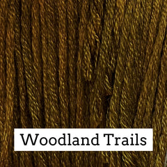 Close-up of rich brown silk embroidery floss with subtle golden and olive tonal variations, labeled “Woodland Trails.”