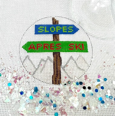 Kate Dickerson Needlepoint Collections Round with Clear Dome and Confetti Slopes and Apres Ski Sign Post Over Sparkly White Slopes Needlepoint Canvas