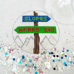 Kate Dickerson Needlepoint Collections Round with Clear Dome and Confetti Slopes and Apres Ski Sign Post Over Sparkly White Slopes Needlepoint Canvas