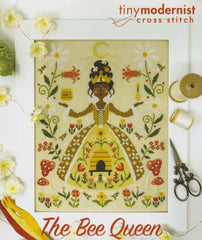 Cross stitch of a Bee Queen in a honey‑gold gown surrounded by buzzing bees, flowers, mushrooms and a tiny beehive scene.