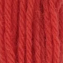 Close-up of sherbert orange crewel wool thread with a soft, fuzzy texture and tightly twisted strands.
