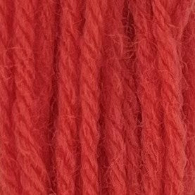 Close-up of sherbert orange tapestry wool thread with a soft, fuzzy texture and tightly twisted strands.
