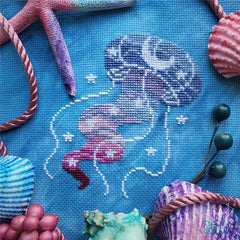 Cross stitch pattern of a jellyfish drifting through a star and moon speckled ocean
