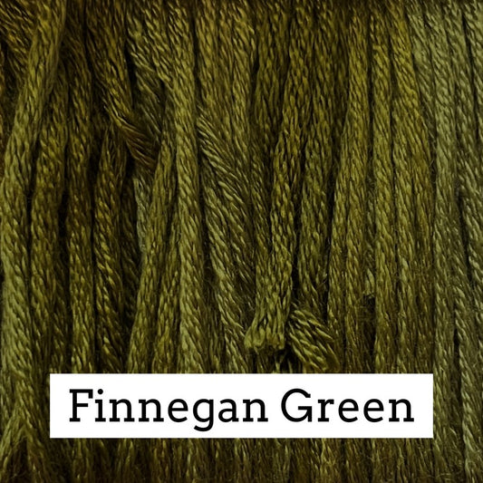 Close-up of olive‑green silk embroidery floss with subtle light and dark variegation, labeled “Finnegan Green.”