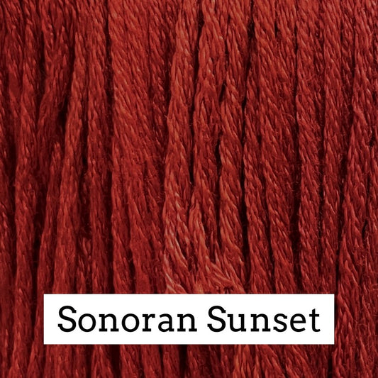 Close-up of deep red silk embroidery floss with subtle darker and lighter variegation, labeled “Sonoran Sunset.”
