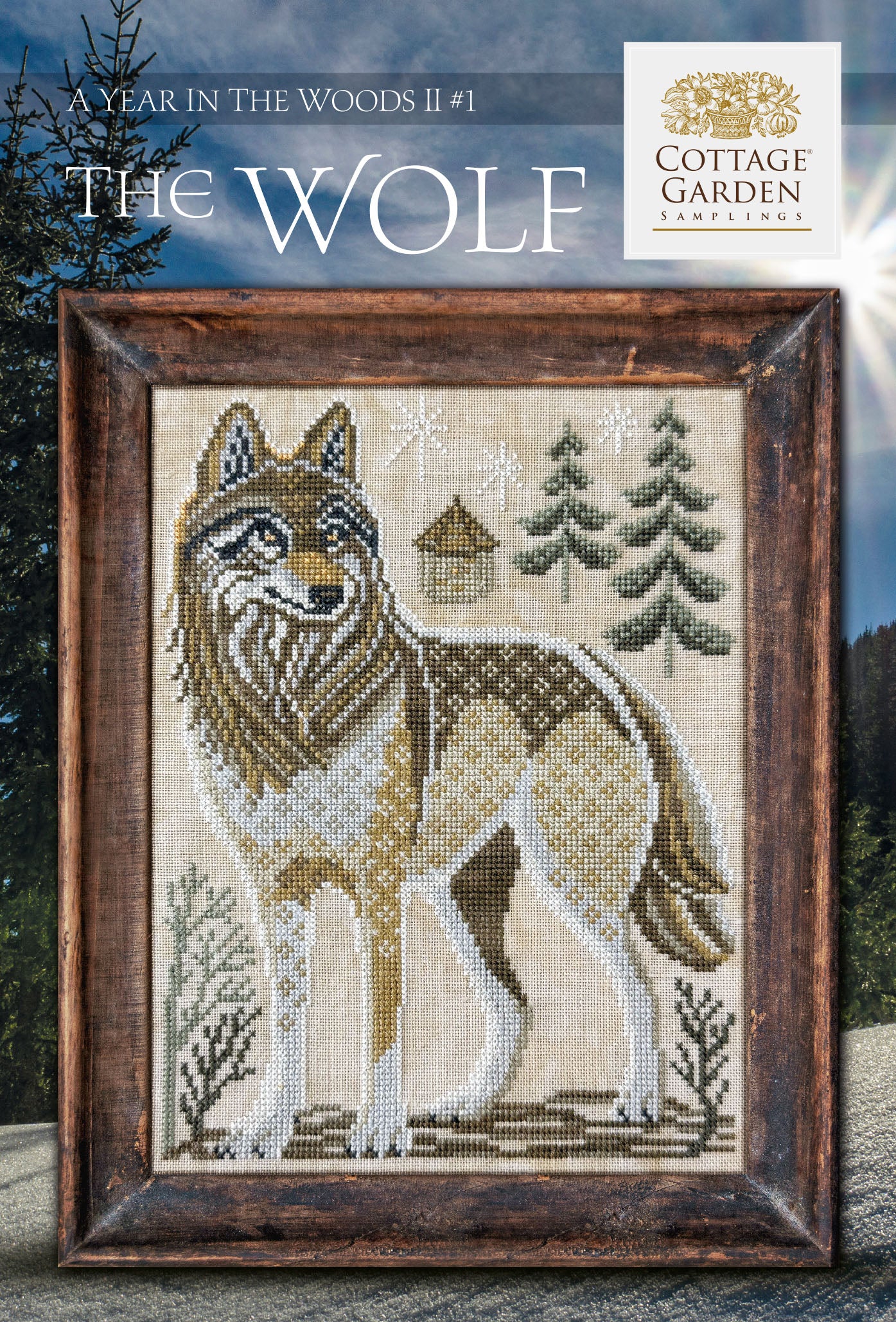 Framed cross stitch of a wolf standing in a snowy woodland landscape with evergreen trees and a small cabin.