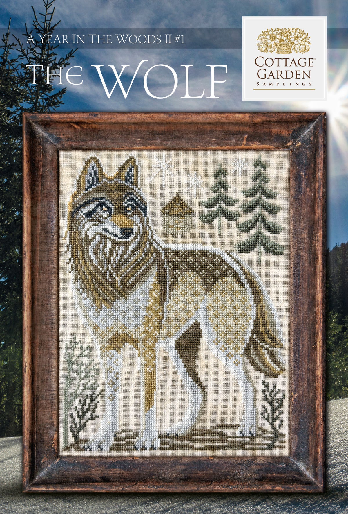 Framed cross stitch of a wolf standing in a snowy woodland landscape with evergreen trees and a small cabin.