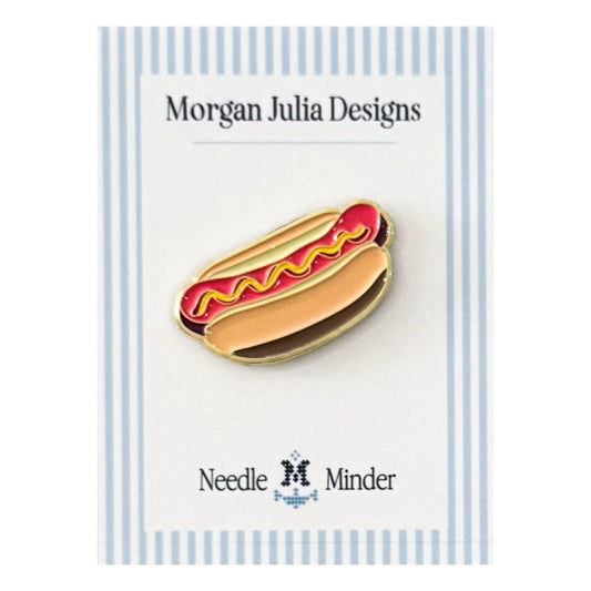 Hot dog–shaped needle minder in a bun with mustard detail, displayed on a Morgan Julia Designs backing card.