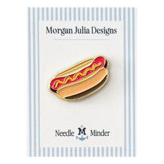 Hot dog–shaped needle minder in a bun with mustard detail, displayed on a Morgan Julia Designs backing card.