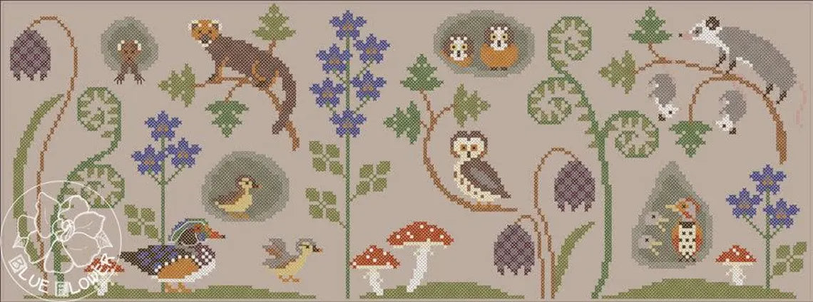 A flat cross stitch scene featuring woodland animals, birds, and mushrooms arranged among ferns and blue flowers in a horizontal layout.