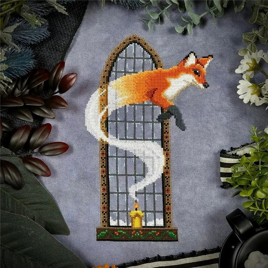 Cross‑stitch of a fox emerging in a swirl of white smoke from a lit candle in front of a tall arched window, surrounded by leafy props.