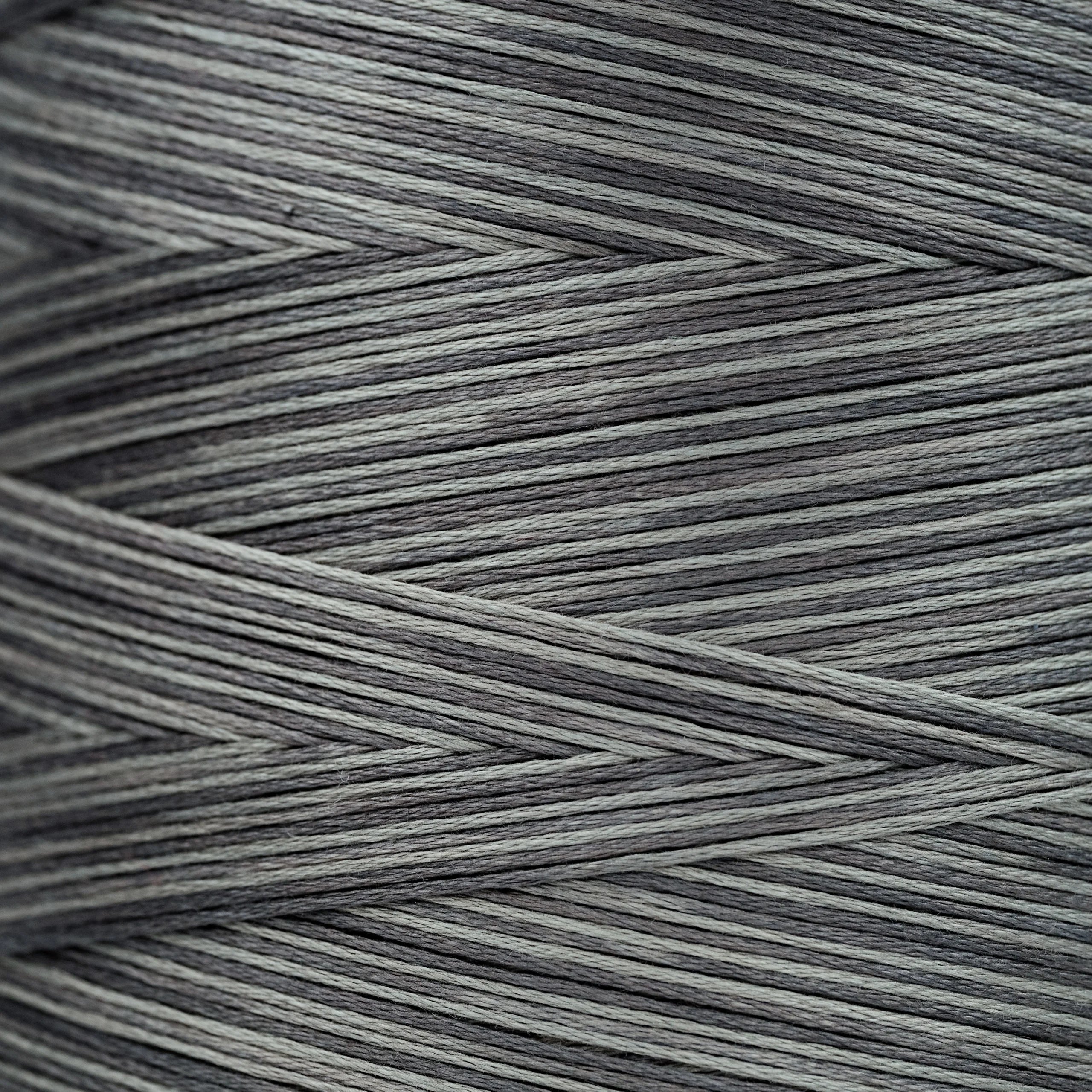 Close-up of gray overdyed embroidery floss wound tightly, showing subtle light and dark tonal variations in the strands.