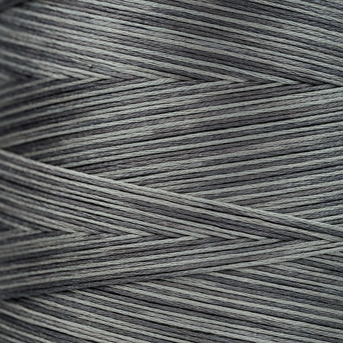 Close-up of gray overdyed embroidery floss wound tightly, showing subtle light and dark tonal variations in the strands.